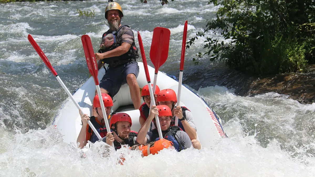 A whitewater raft navigating a powerful rapid and large drop on the Edge of the World rapid on the Chattooga River, showcasing a challenging guided run.