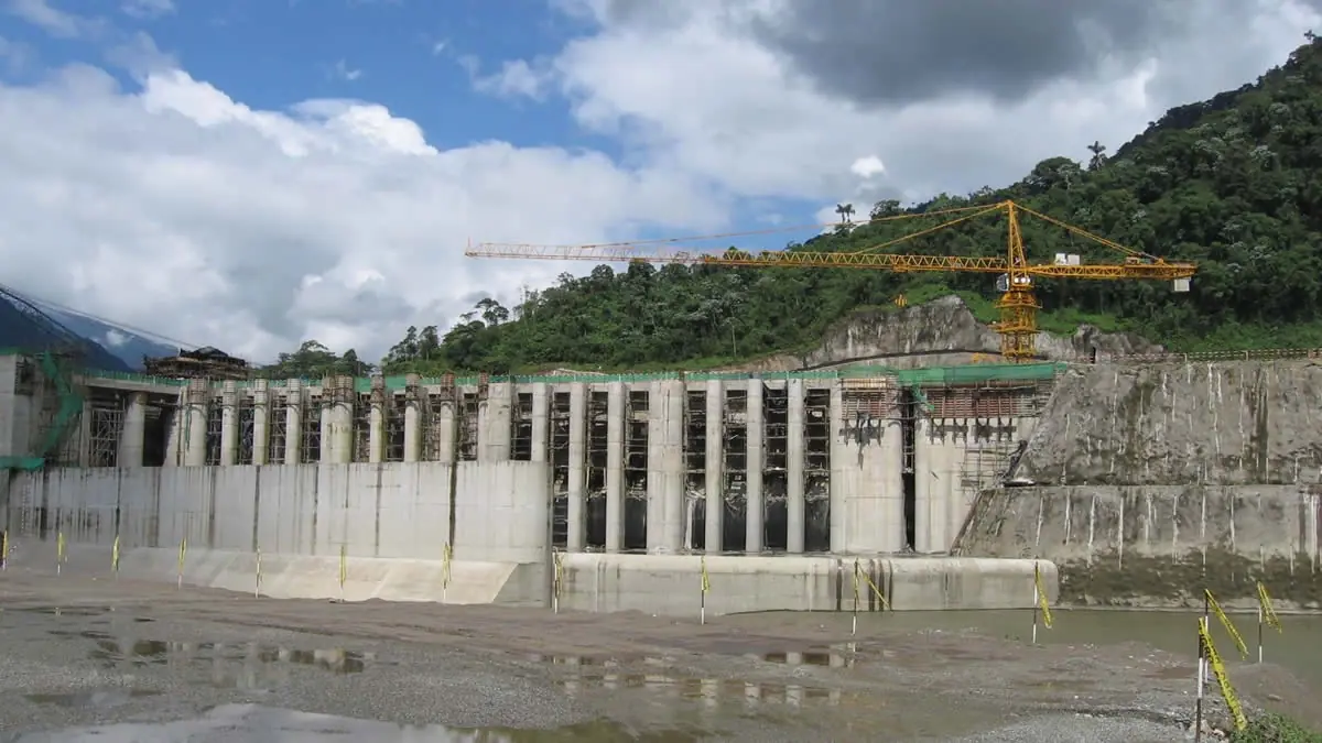Construction site of the Rio Quijos Hydroelectric Project featuring a large concrete dam structure and construction crane in Ecuador