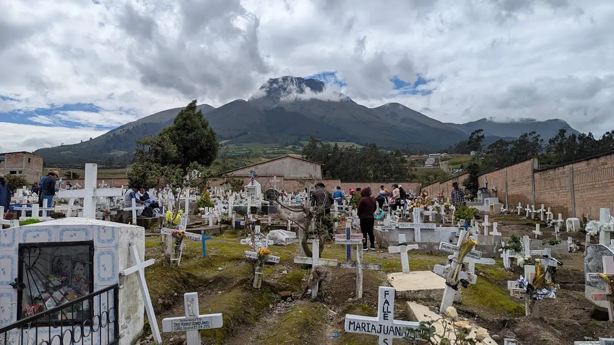 Traditional Day of the Dead (Día de los Difuntos) observances in a cemetery in Otavalo, Ecuador, featuring families honoring ancestors with food and flowers