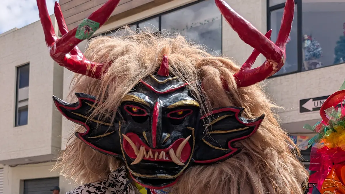A close-up view of an intricate and fearsome devil mask worn during the Diablada Pillareña festival in Ecuador