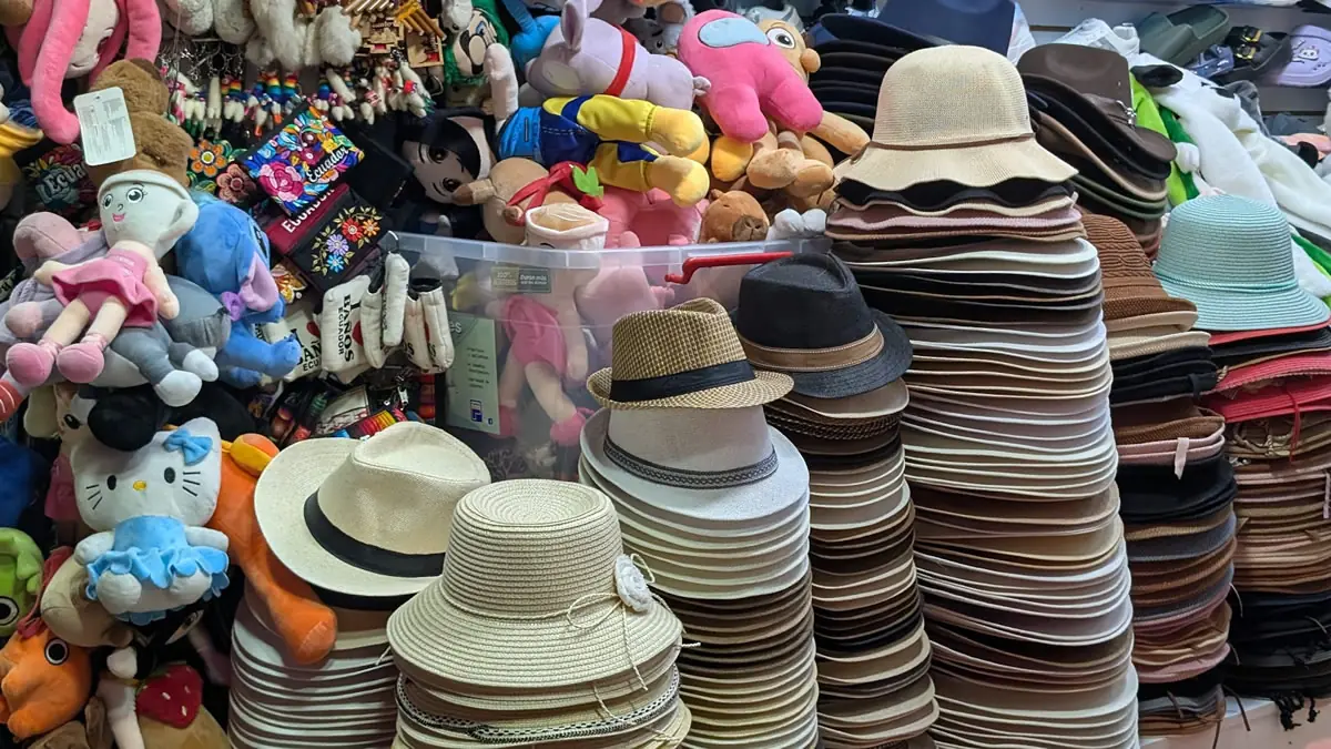 Stacks of authentic hand-woven straw hats, known globally as Panama Hats, on display at a local market in Ecuador.