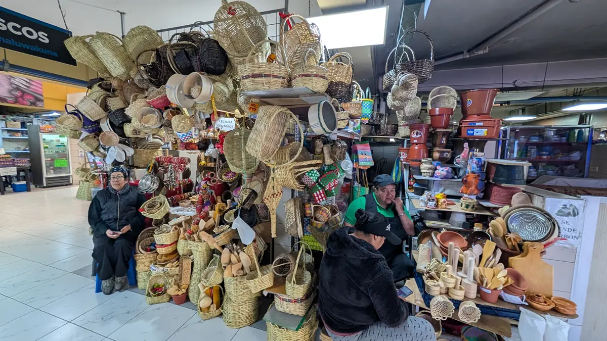 Stall featuring traditional handmade baskets and wooden kitchen utensils at Mercado Central in Quito, Ecuador.