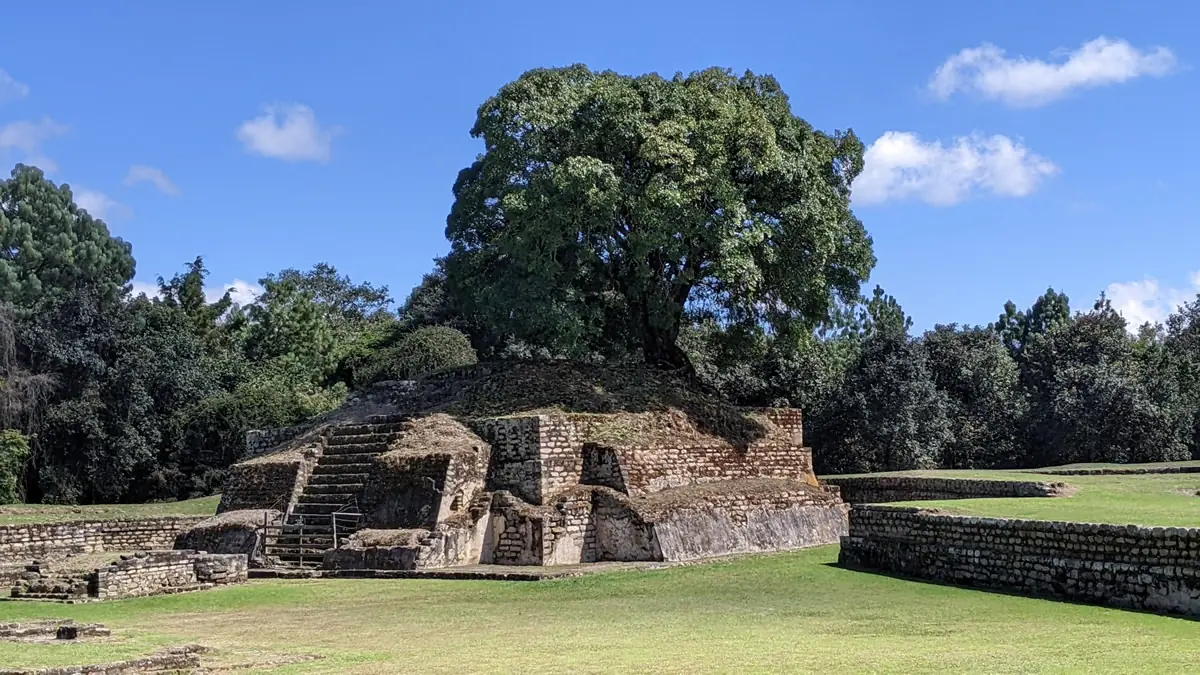 Ancient Mayan pyramid at Iximche ruins surrounded by lush green trees in Guatemala