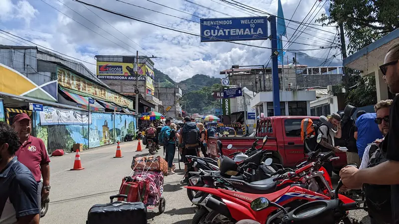 Crowded scene at the Mexico-Guatemala border crossing with shuttles and luggage