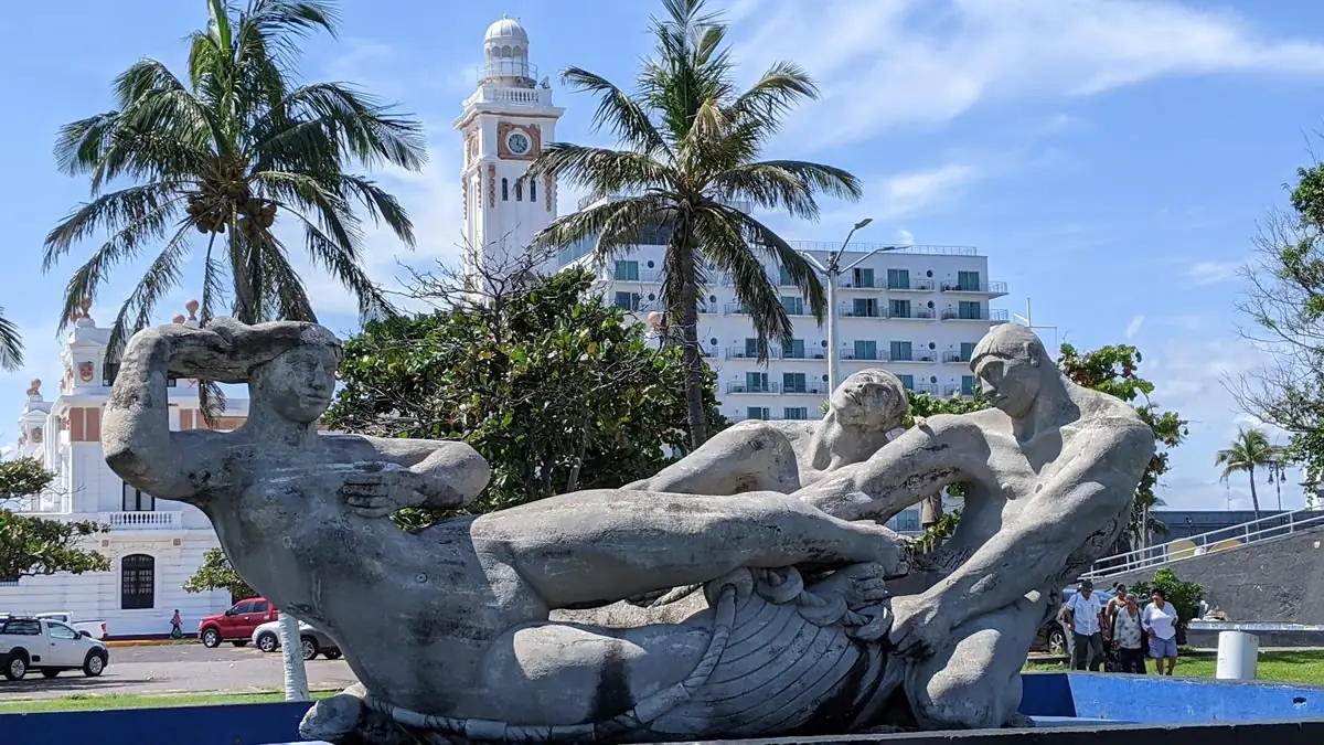 The sculpture 'La Riqueza del Mar' (The Wealth of the Sea) on the Malecón of Veracruz, with the historic Venustiano Carranza Lighthouse in the background.