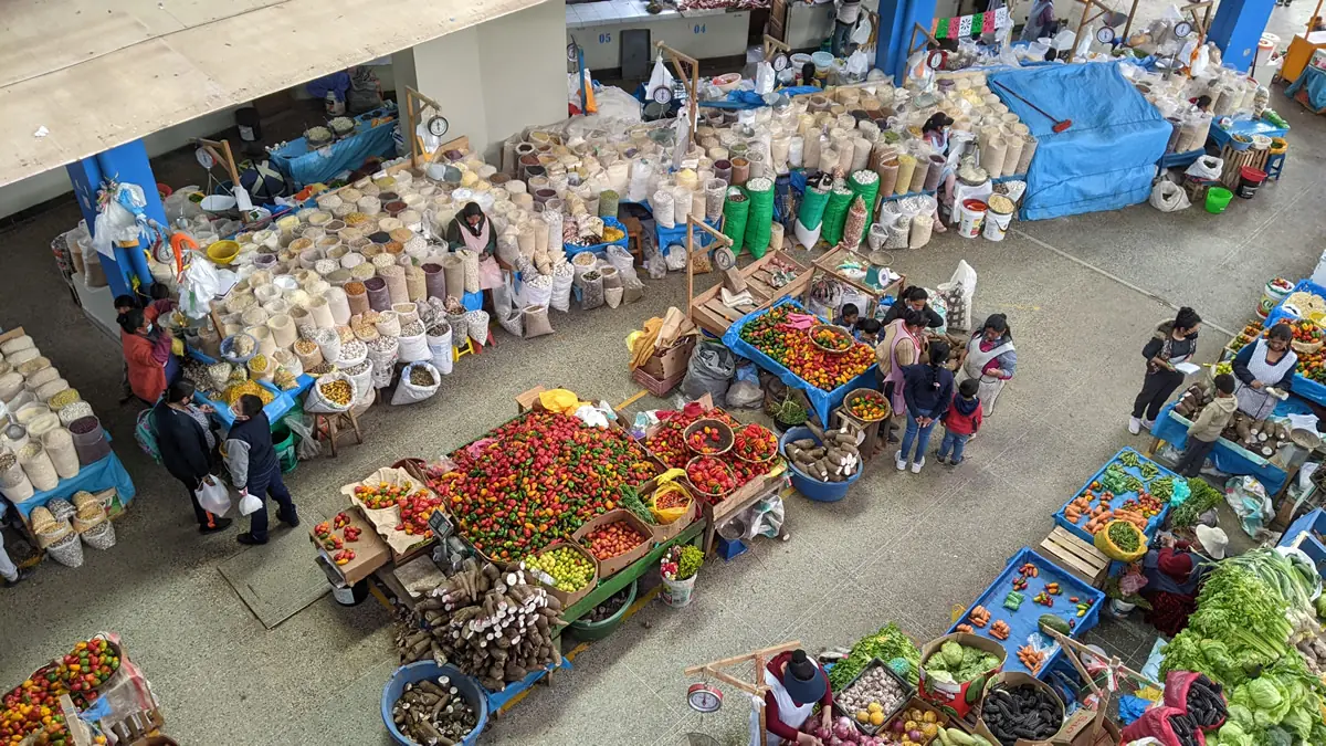 A panoramic view from the third floor overlooking the bustling local mercado in Urubamba, Peru, with the Andes mountains in the background.