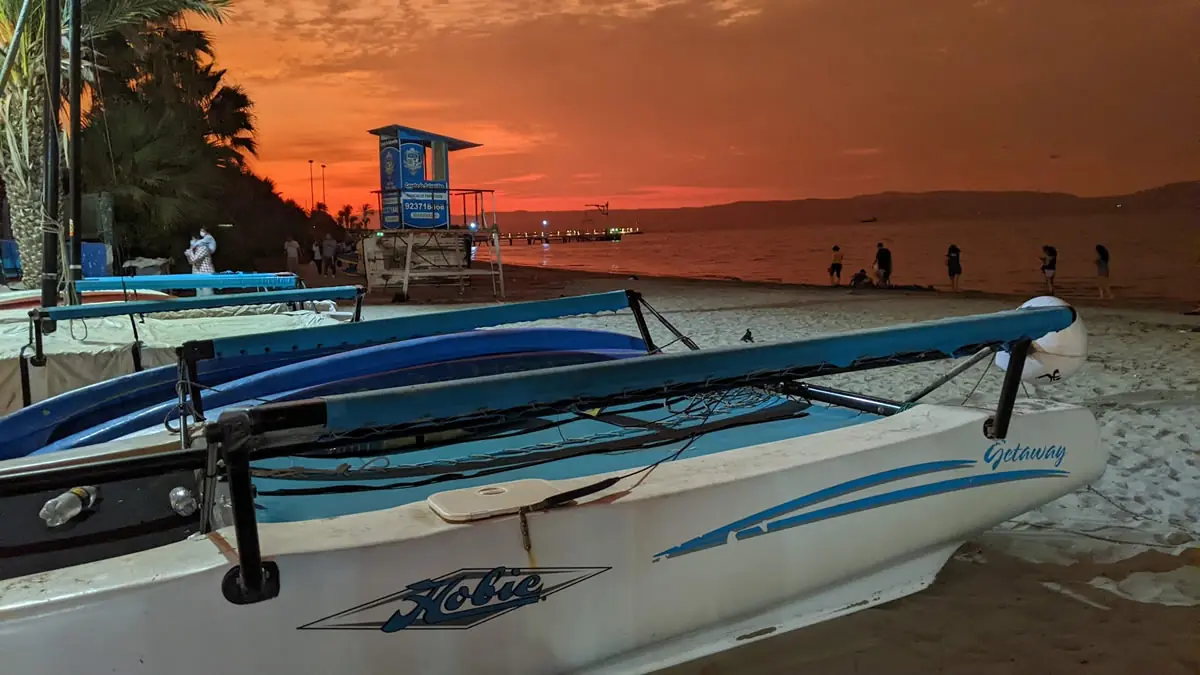 Hobie Getaway sailboat resting on the beach during a red sunset in Paracas, Peru.