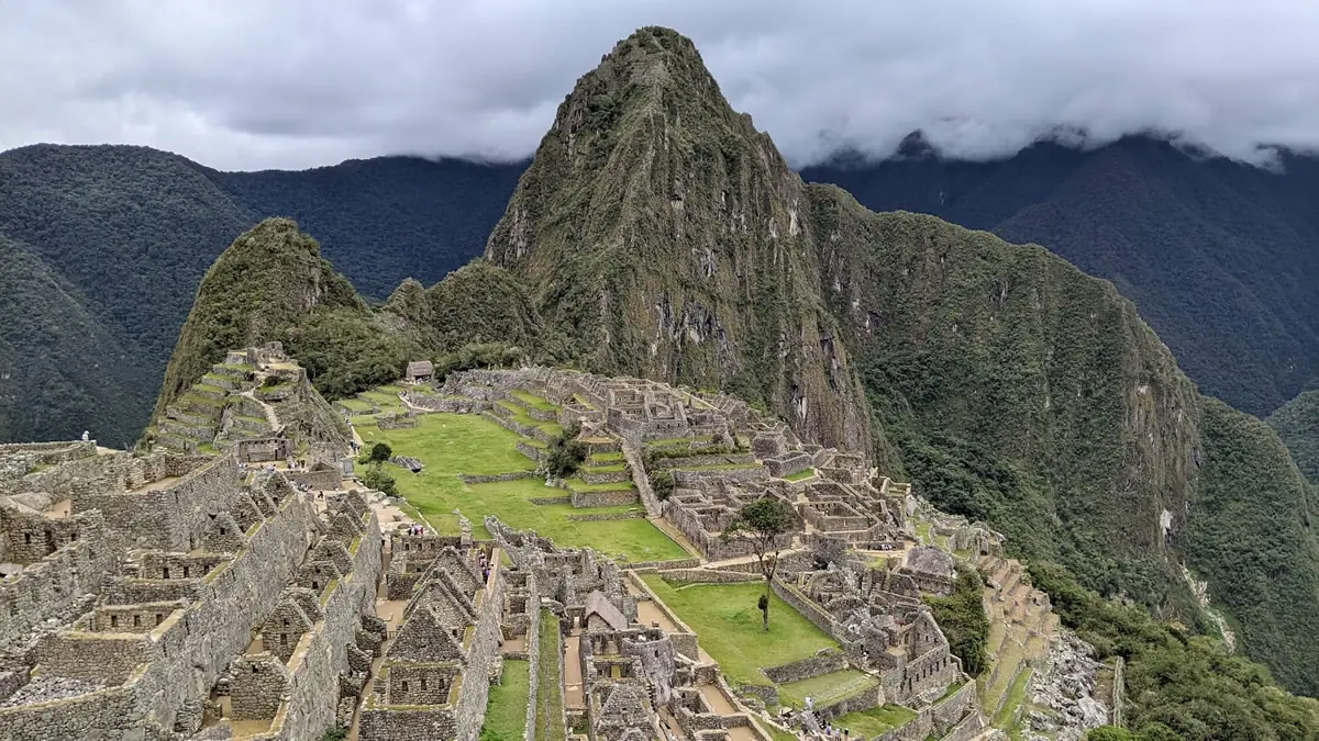 The ancient Inca citadel of Machu Picchu with distant mountains shrouded in mist and low clouds during the rainy season in Peru.