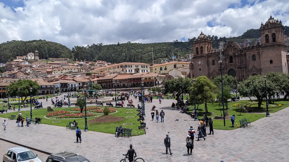 View across Plaza de Armas in Cusco, Peru featuring the Cusco Cathedral, with the San Cristobal church and the ancient ruins of Saqsaywaman in the background.