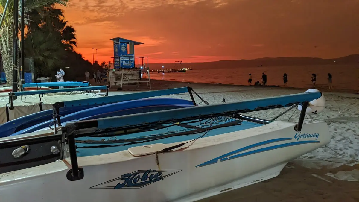 Vibrant orange sunset over the Pacific Ocean at Paracas beach with Hobie Getaway boats parked on the sand